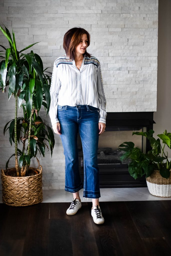 Midlife Women wearing Golden Goose sneakers, flair jeans and embroidered Top