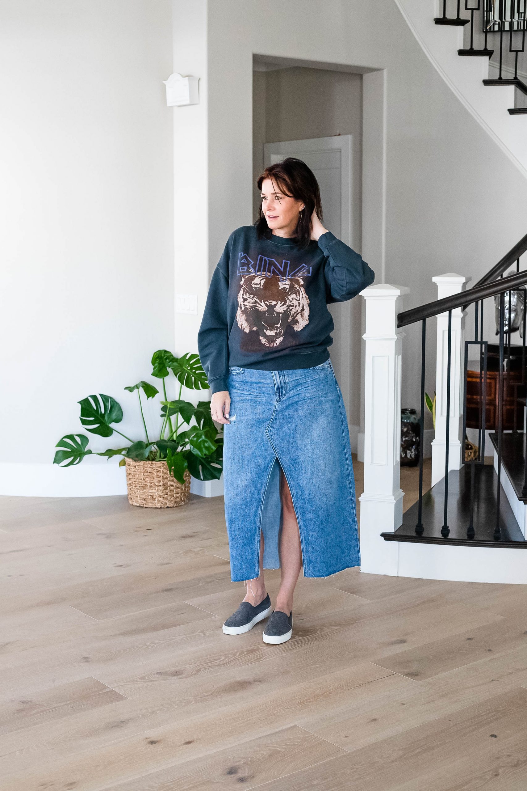 Midlife women wearing long denim skirt with graphic sweatshirt and sneakers