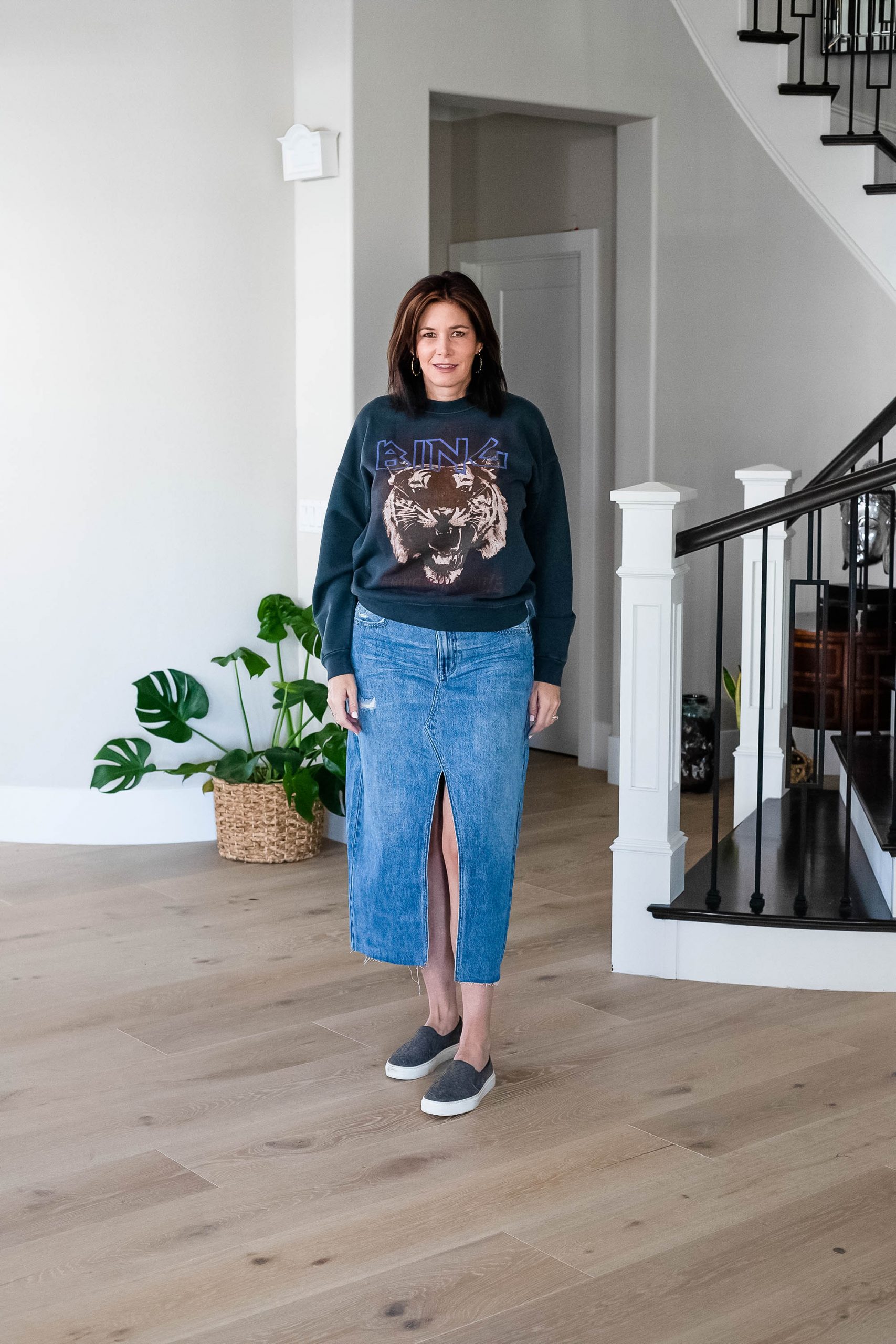 Midlife women wearing long denim skirt with graphic sweatshirt and sneakers