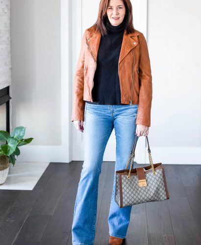 Midlife women wearing black turtleneck, Madewell leather jacket and boot-cut denim with Gucci Purse