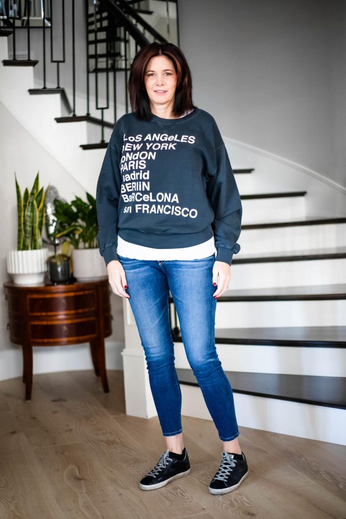 Over 50 women wearing graphic sweatshirt, jeans and sneakers
