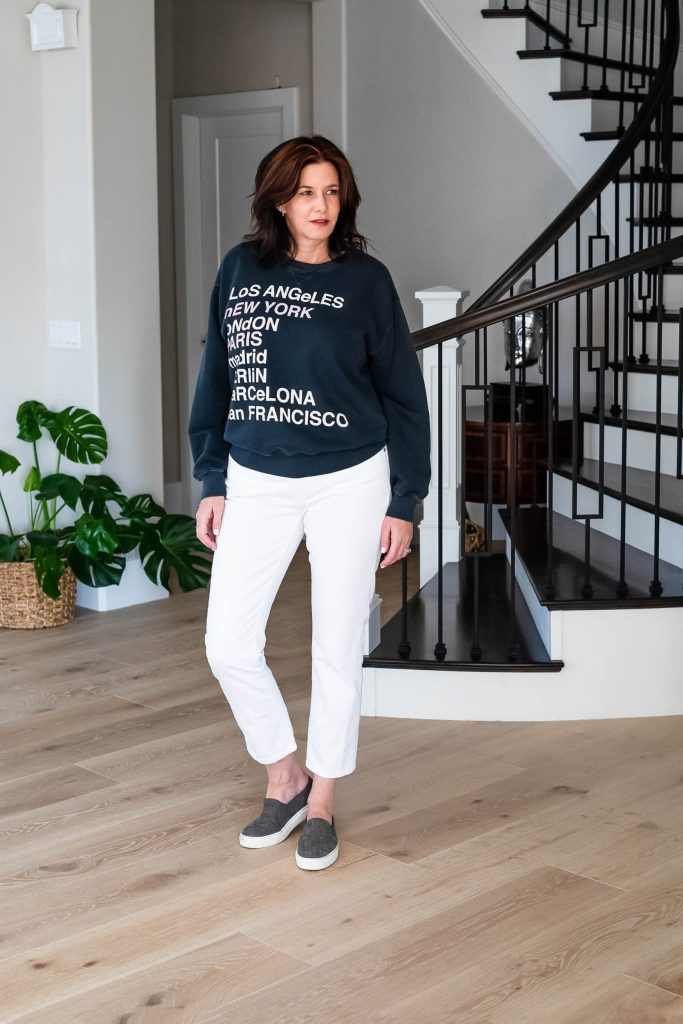 Over 50 women wearing graphic sweatshirt with white jeans