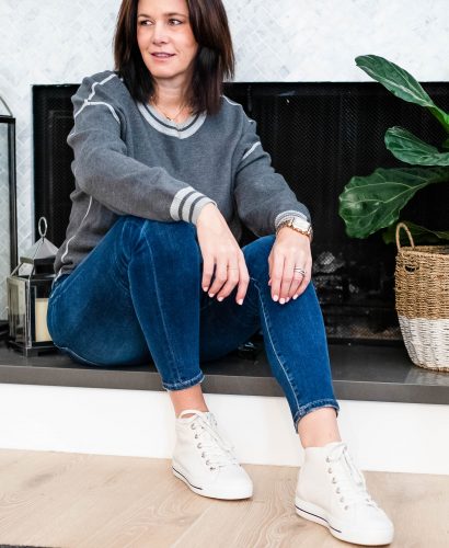 Midlife women sitting wearing white sneakers, jeans and grey sweater