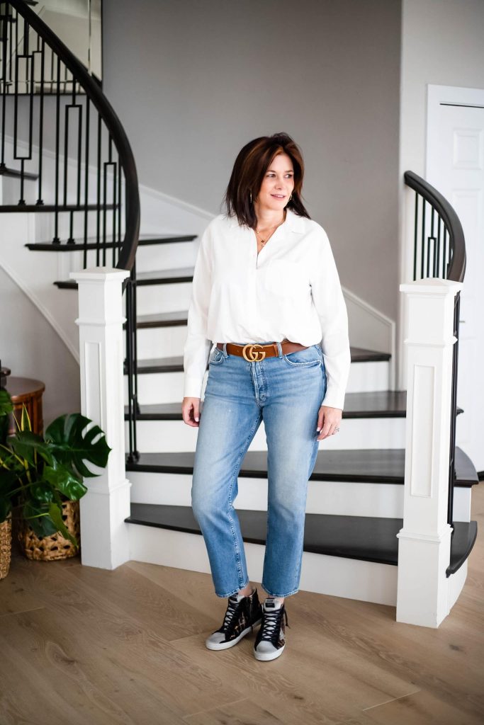 Over 50 women wearing white shirt and straight leg denim jeans with Golden Goose Sneakers