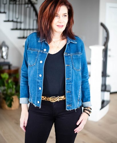 Midlife women wearing all black outfit with leopard belt and denim jacket