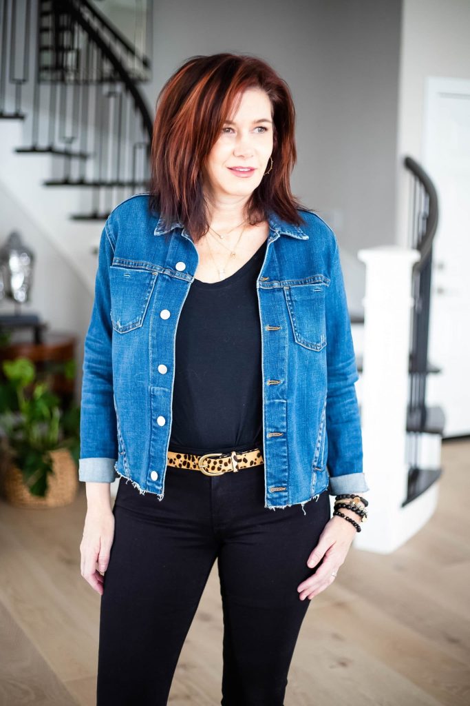 Midlife women wearing all black outfit with leopard belt and denim jacket