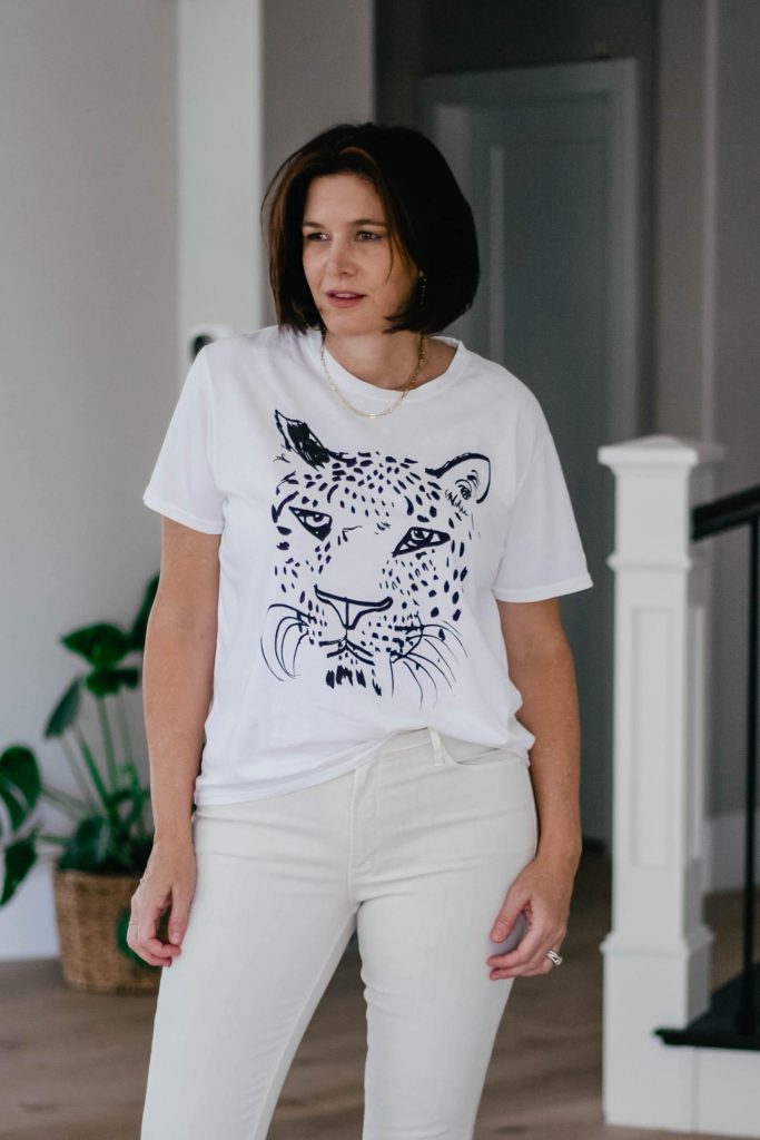 Midlife women wearing ivory denim with Clare V by Anthropologie tee and sandals.