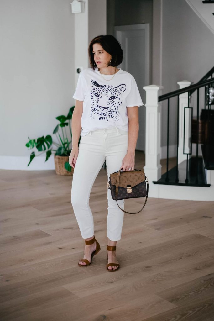 Midlife women wearing ivory denim with Clare V by Anthropologie tee and sandals.