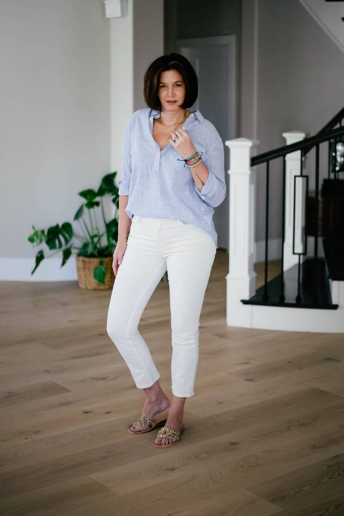 Midlife women wearing ivory jeans, striped popover top and leopard sandals.