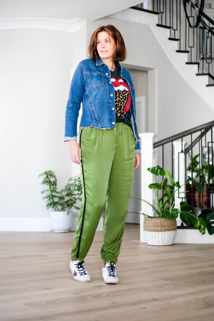 Over 50 women wearing satin joggers, graphic tee, L'agence denim jacket and sneakers