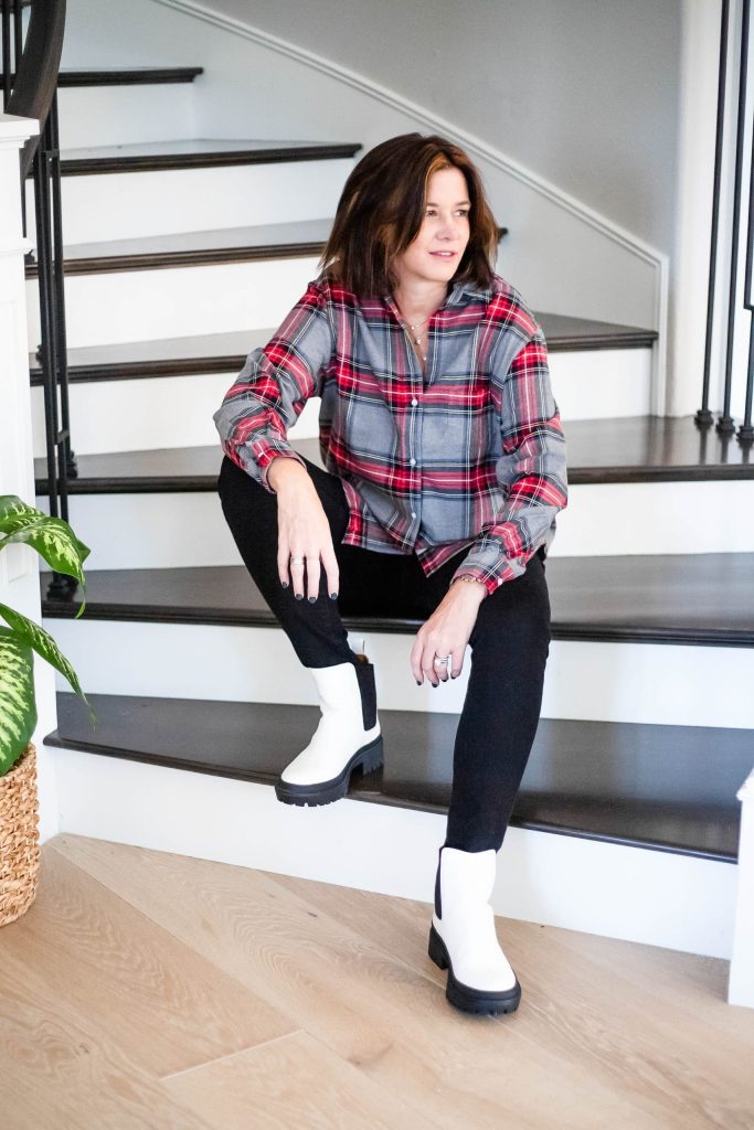 Over 50 women wearing flannel shirt, black jeans and white lug sole boots.