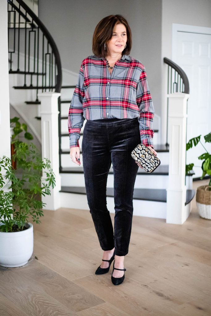 Midlife women wearing plaid flannel shirt, velvet pants and sequin purse.