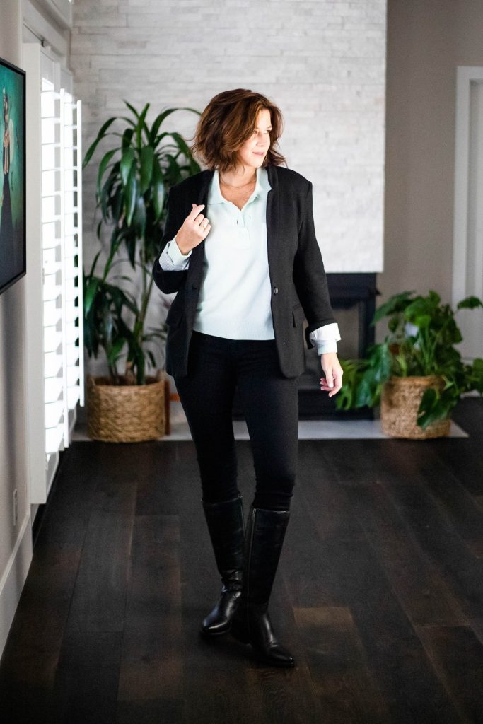 Midlife women wearing cashmere sweater, black jeans, boots and blazer. 