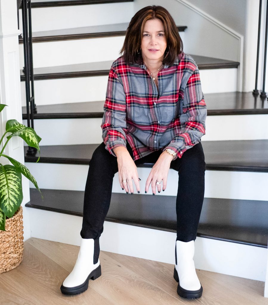 Women sitting on stairs in flannel shirt, black jeans and white combat boots.