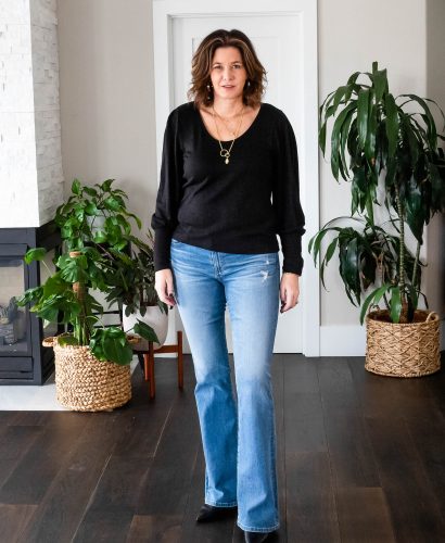 Midlife women wearing bootcut jeans, black sweater and heels.