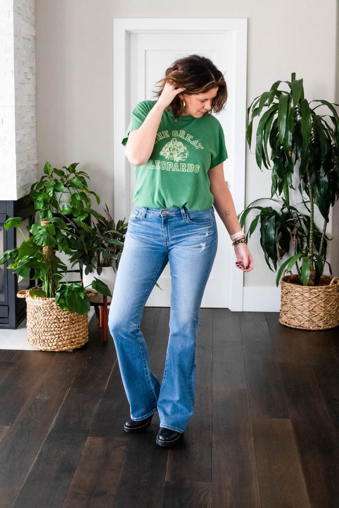 Over 50 women wearing bootcut jeans and green graphic tee.