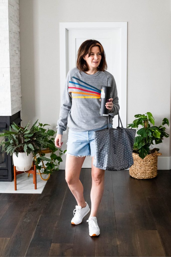 Midlife women wearing Agolde Parker Shorts, Aviator Nation Sweatshirt and sneakers