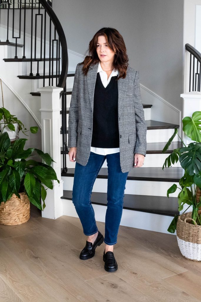 Midlife women wearing sweater vest, button down shirt, plaid blazer, straight leg jeans and loafers