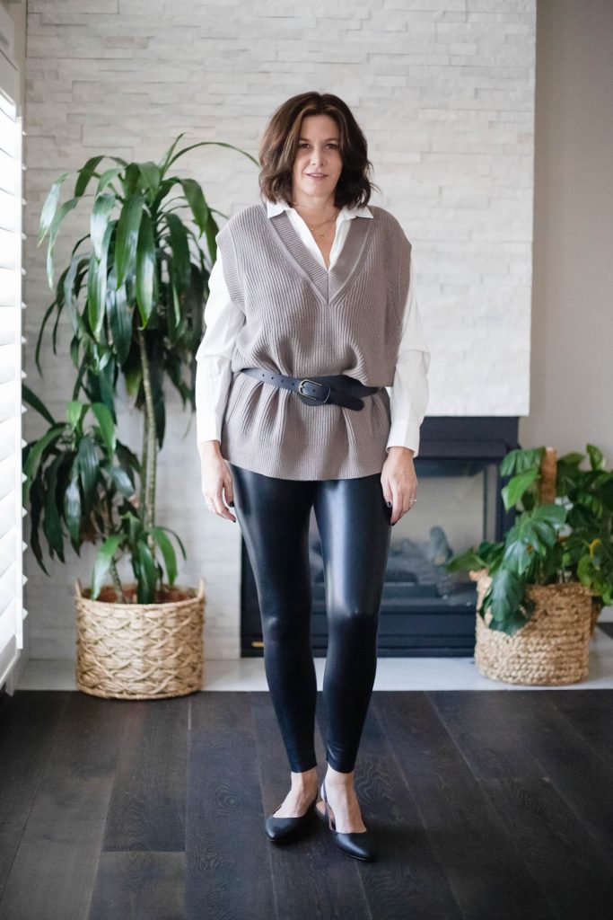 Midlife women wearing sweater vest, button down shirt, faux leather leggings and heels.